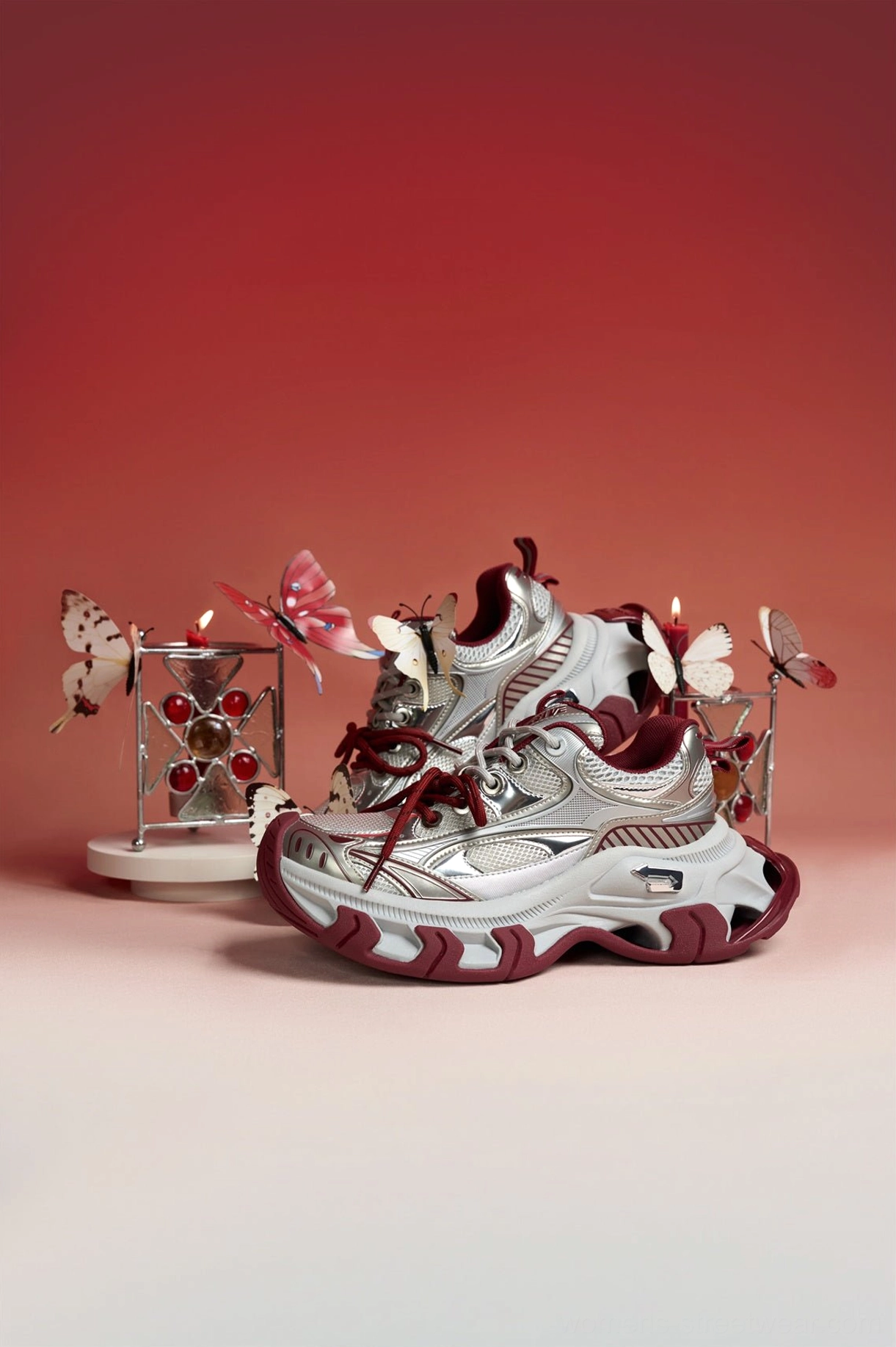 Front three-quarter view of red and silver chunky platform sneakers with burgundy laces, bold toe box, and futuristic streetwear design