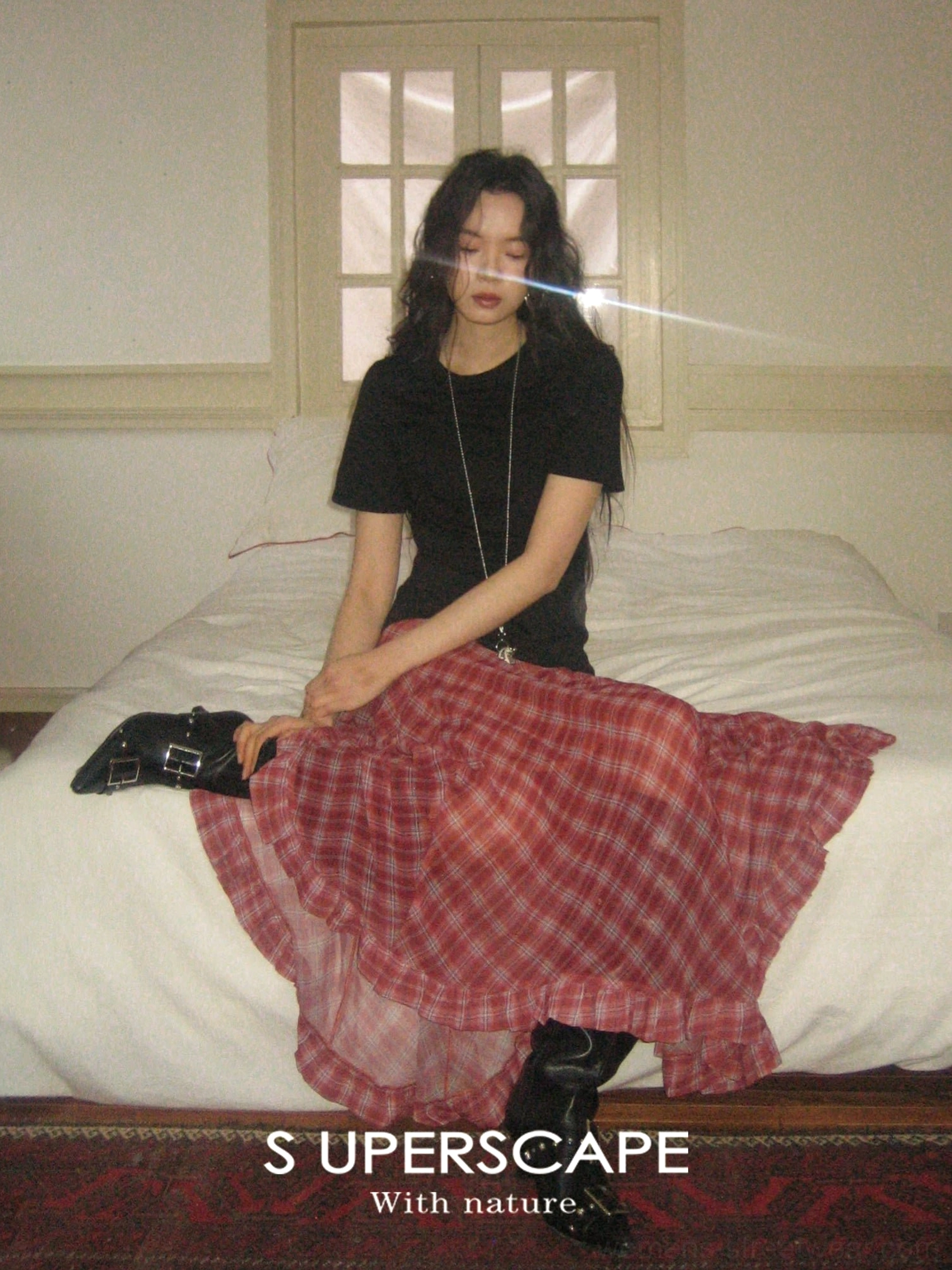 Red plaid chiffon skirt with ruffled asymmetric hem shown from an overhead seated view on a bedroom bed