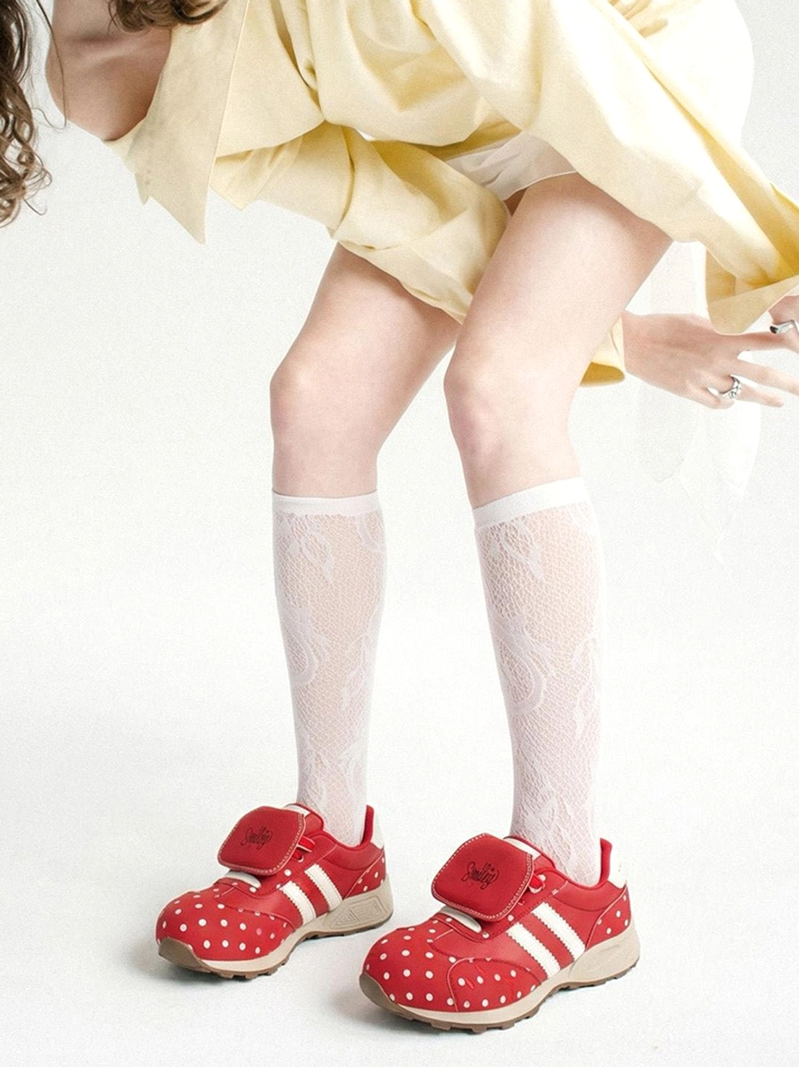 Red polka dot platform sneakers worn with a loose yellow top and white lace socks in a Korean fashion outfit