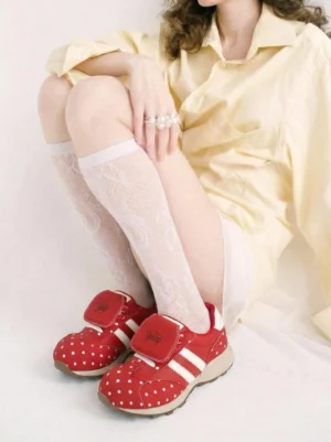 Red polka dot streetwear sneakers styled with a yellow oversized shirt and white lace knee high socks