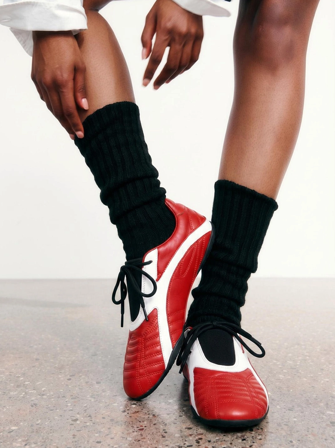 Close-up of red quilted flat sole sneakers worn with tall black crew socks in a minimalist Korean streetwear outfit
