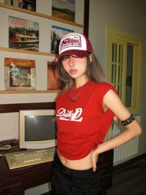 Front view of a women's red retro Americana cropped T-shirt with white Dillo D script graphic, styled with a trucker hat and silver star necklace