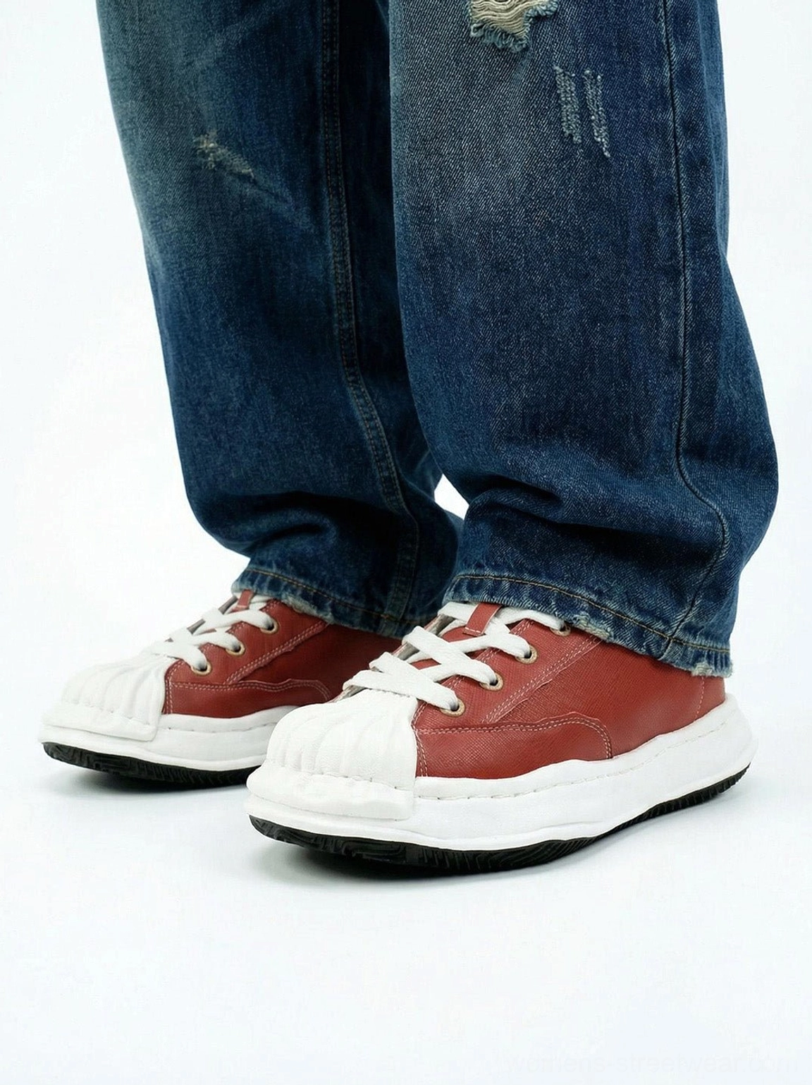 Red shell-toe court sneakers styled with dark blue ripped straight-leg jeans in a casual streetwear outfit