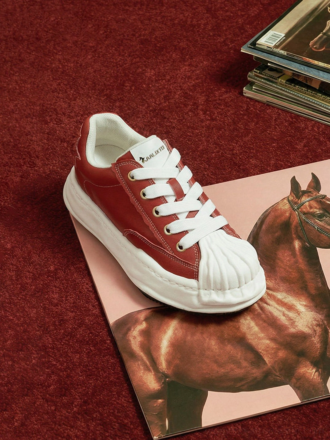 Close three-quarter view of a red shell-toe sneaker showing the lace system, molded toe cap, and chunky outsole