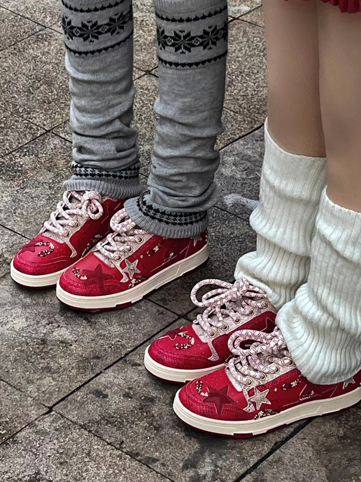 Two people wearing red snake-embossed star sneakers with grey knitted and white ruffled leg warmers in casual street style