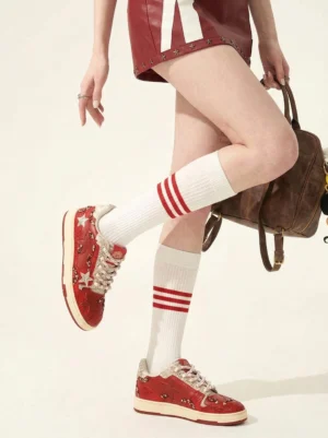 Female model wearing red snake-embossed star sneakers with a red mini skirt, striped socks, and Y2K streetwear styling
