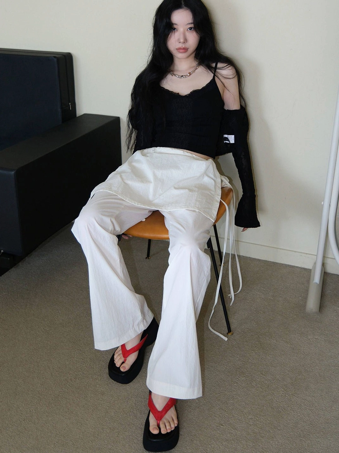 Red strap black platform flip-flops paired with relaxed black top and white wide-leg trousers