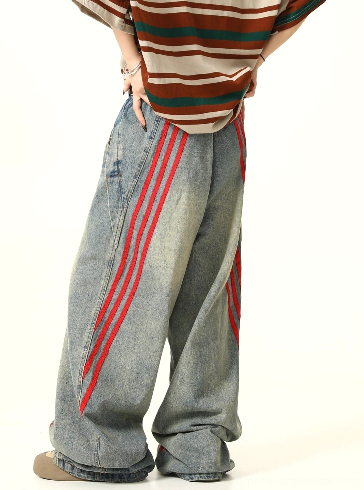 Side view of drapey wide-leg light wash denim jeans with red diagonal triple stripes and subtle thigh fading