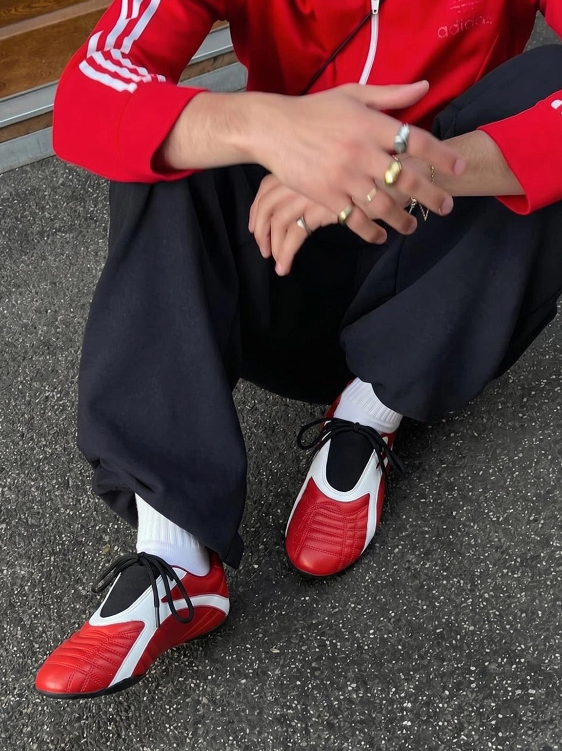Red and white quilted streetwear sneakers styled with a red track jacket, black sweatpants, and white crew socks on city pavement