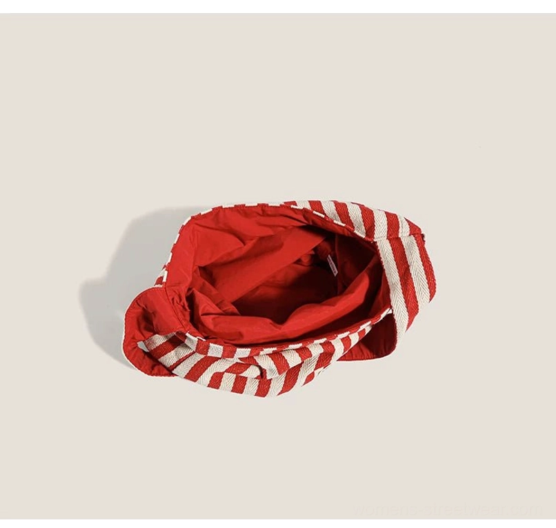 Open interior of red and off-white striped canvas hobo bag showing red polyester lining and spacious main compartment