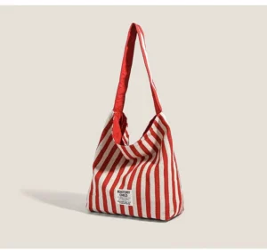 Three-quarter view of red and off-white striped canvas hobo bag with soft unstructured market tote shape