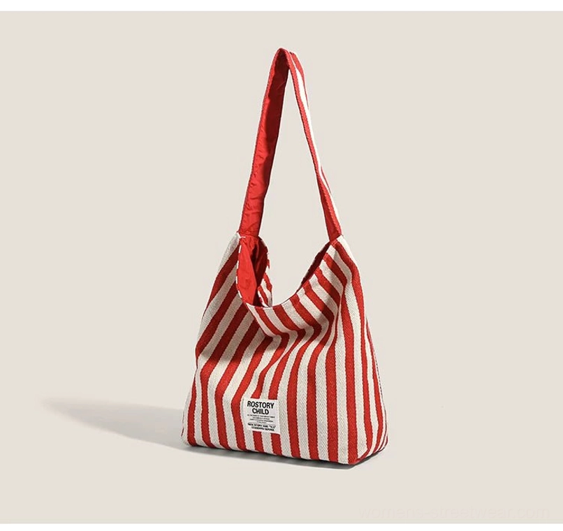 Three-quarter view of red and off-white striped canvas hobo bag with soft unstructured market tote shape
