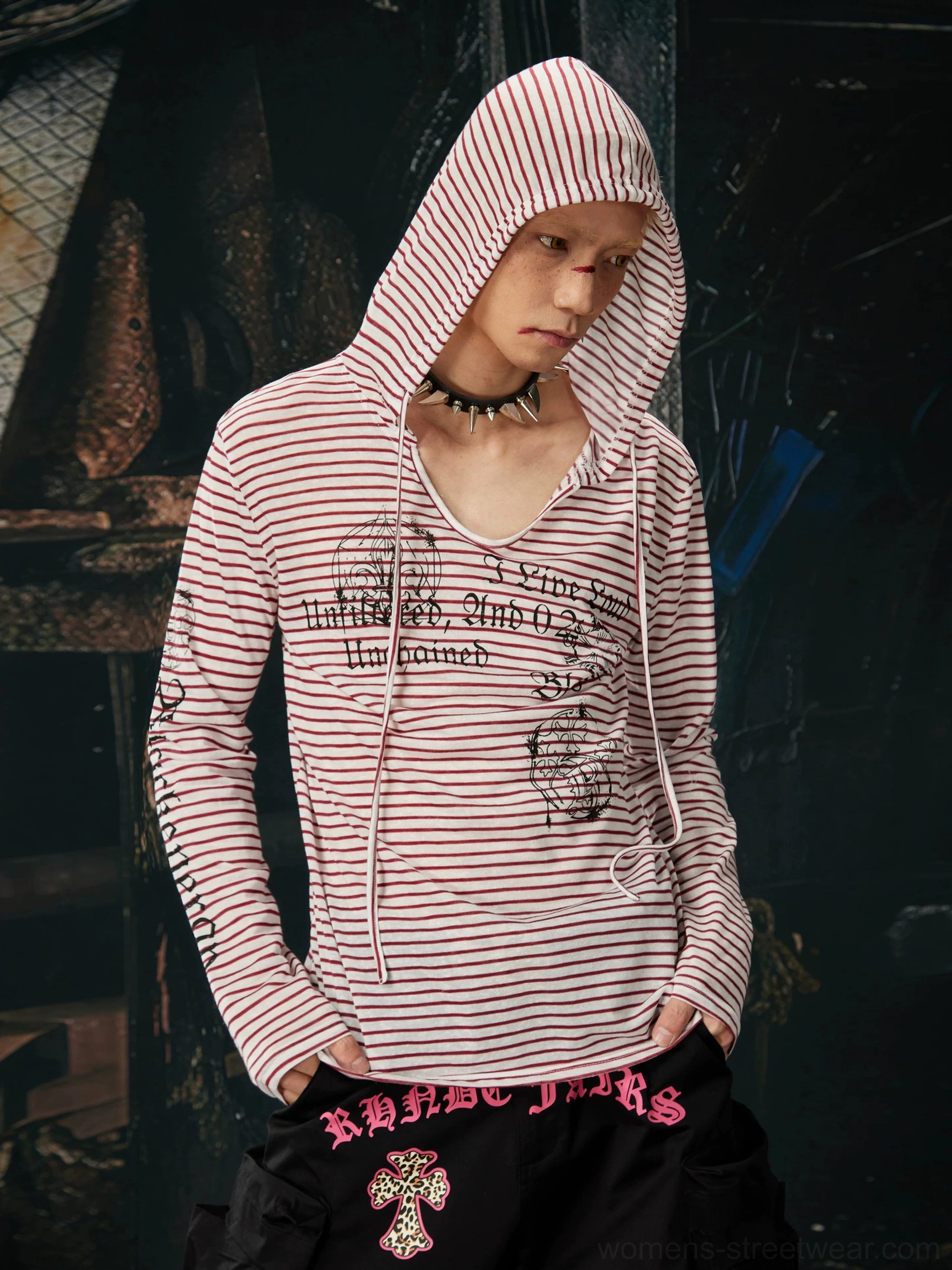 Side front view of a red and white striped gothic hooded long sleeve top with script graphics and a slim streetwear silhouette