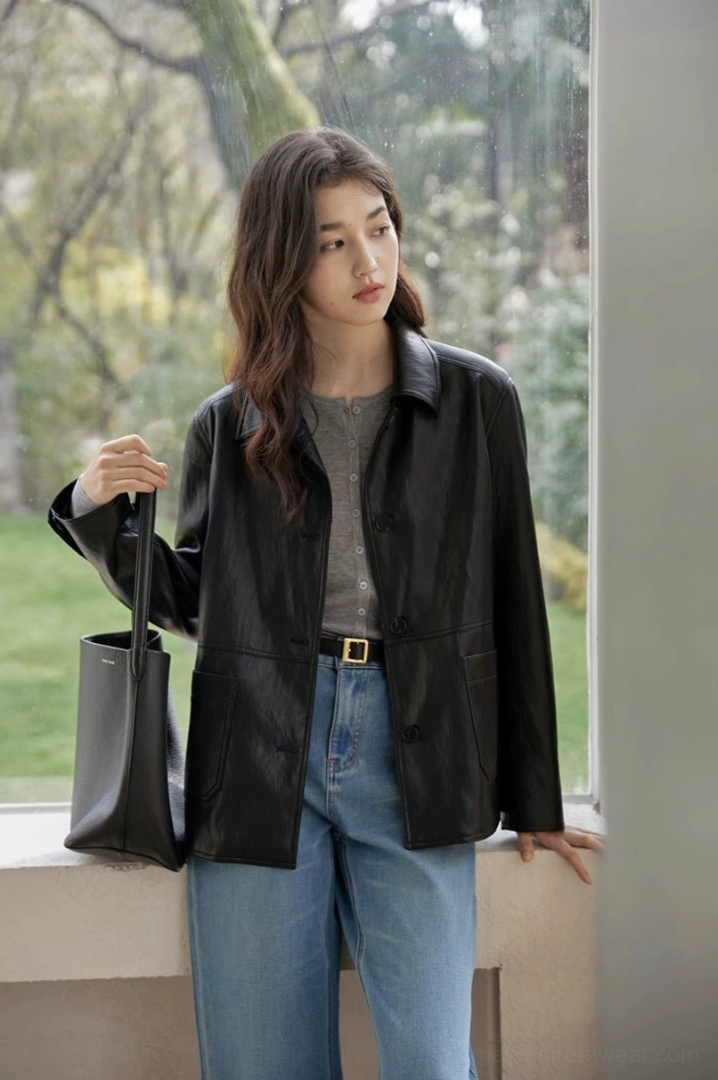 Front three-quarter view of a relaxed black leather-look jacket with smooth matte finish and button placket