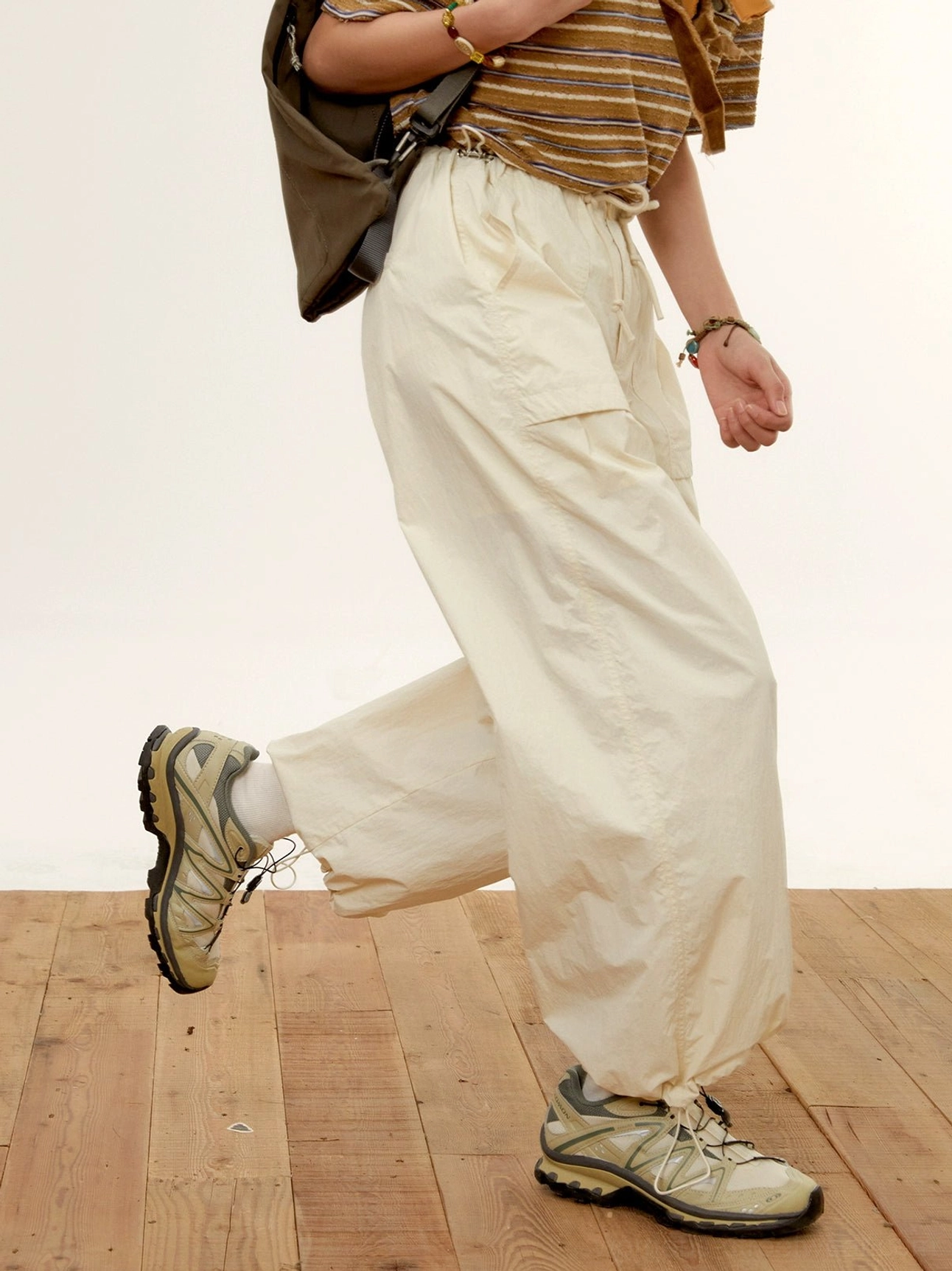 relaxed nylon cargo pants cream white dynamic side walking view outdoor hiking backpack shoes