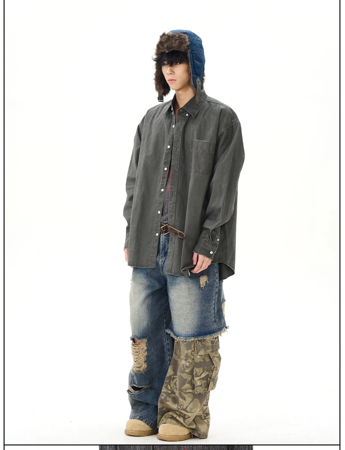 Front view of relaxed distressed patchwork wide-leg jeans styled with a long-sleeve top, featuring vintage washed denim, camo lower-leg panels, and rugged frayed details