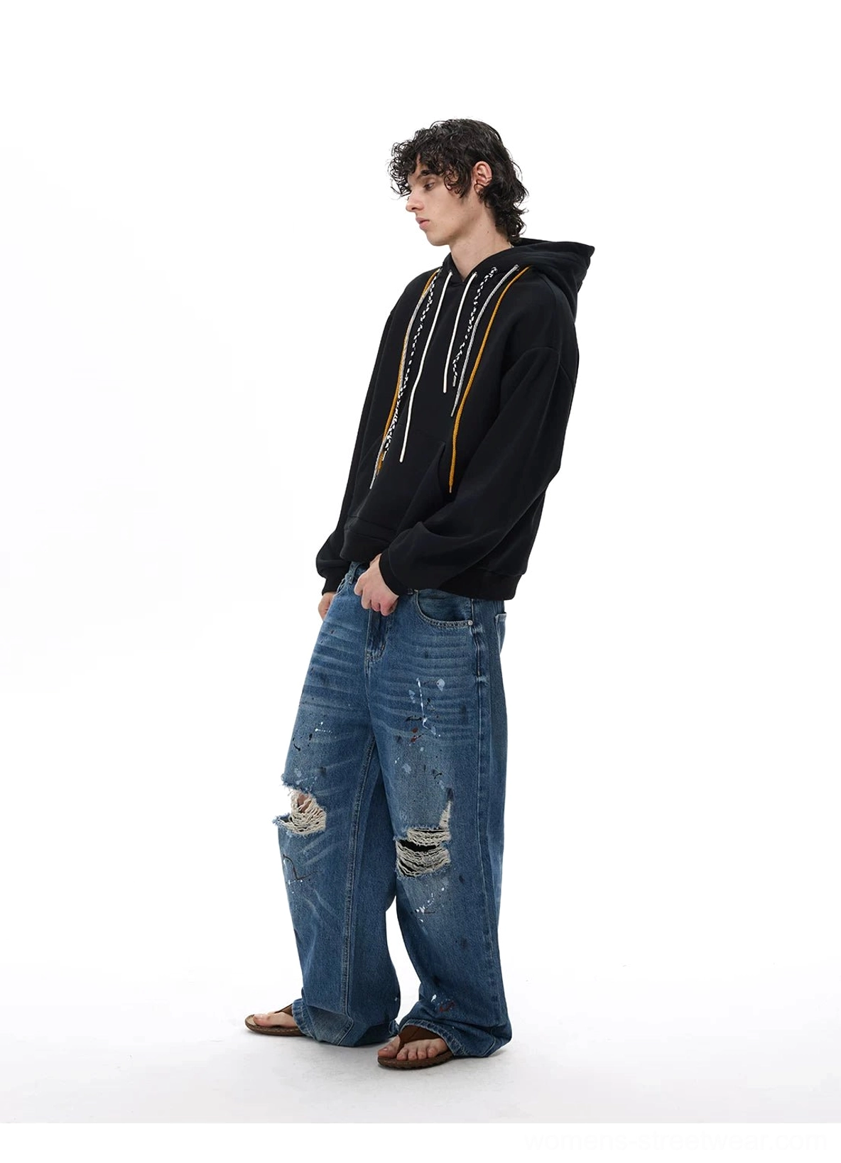 Side profile of relaxed distressed wide-leg jeans with faded thigh treatment, frayed knees, and vintage washed denim