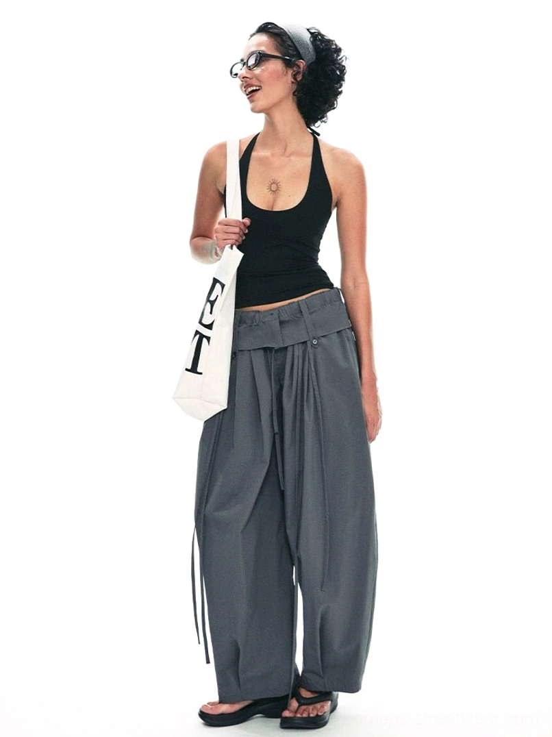 Dark gray relaxed drawstring paperbag wide-leg streetwear trousers styled with black tank top and canvas tote front three-quarter view
