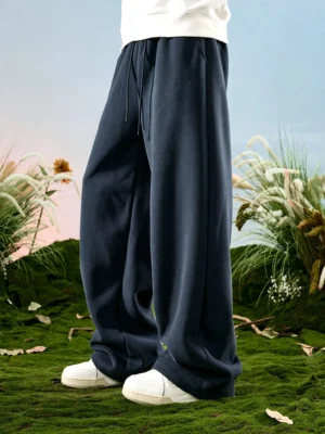 Navy blue relaxed drawstring wide-leg sweatpants side view with white sneakers in an outdoor streetwear setting