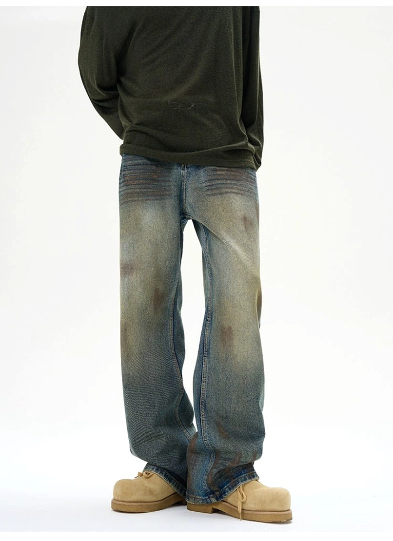 Relaxed fit distressed denim jeans with faded blue wash, rugged abrasions, and loose baggy streetwear construction
