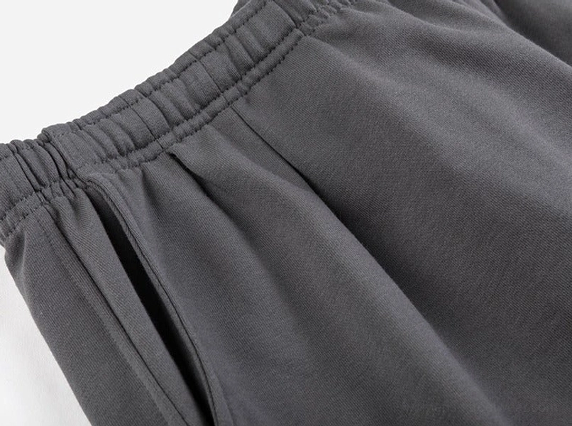 Detailed side view of relaxed fit shorts showing elastic waistband, side pocket opening and precise stitched seam construction