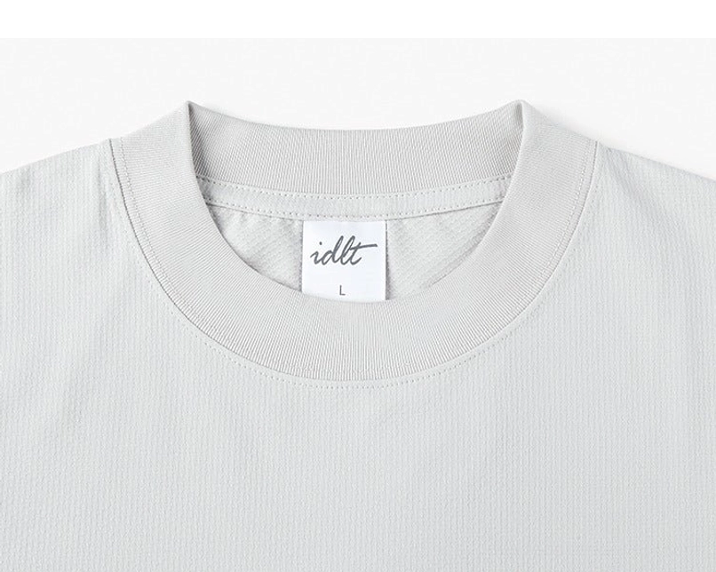 Close-up of ribbed crew neck and woven fabric texture on oversized relaxed fit sweater tee