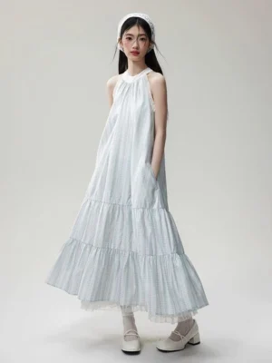 Back three-quarter view of a relaxed gingham halter maxi dress with lace trim, layered ruffled skirt, side pockets, and flowing organza texture