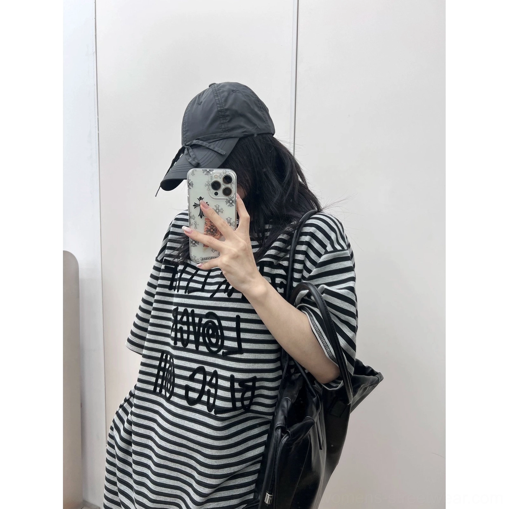 Back-facing mirror view of a relaxed oversized striped graphic T-shirt styled with a large leather shoulder bag for everyday city wear