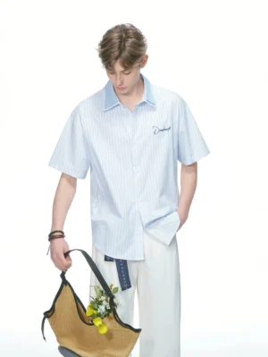 Blue and white vertical pinstripe short sleeve contrast collar shirt styled with white wide leg trousers and a woven floral tote bag