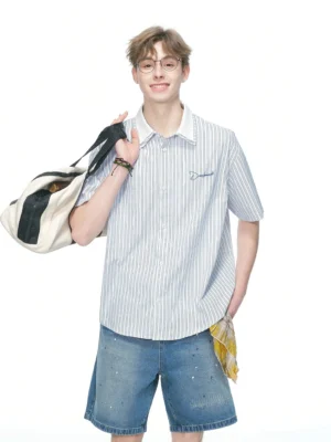 Blue and white pinstripe short sleeve button up streetwear shirt with contrast collar styled with distressed denim shorts and canvas duffle bag
