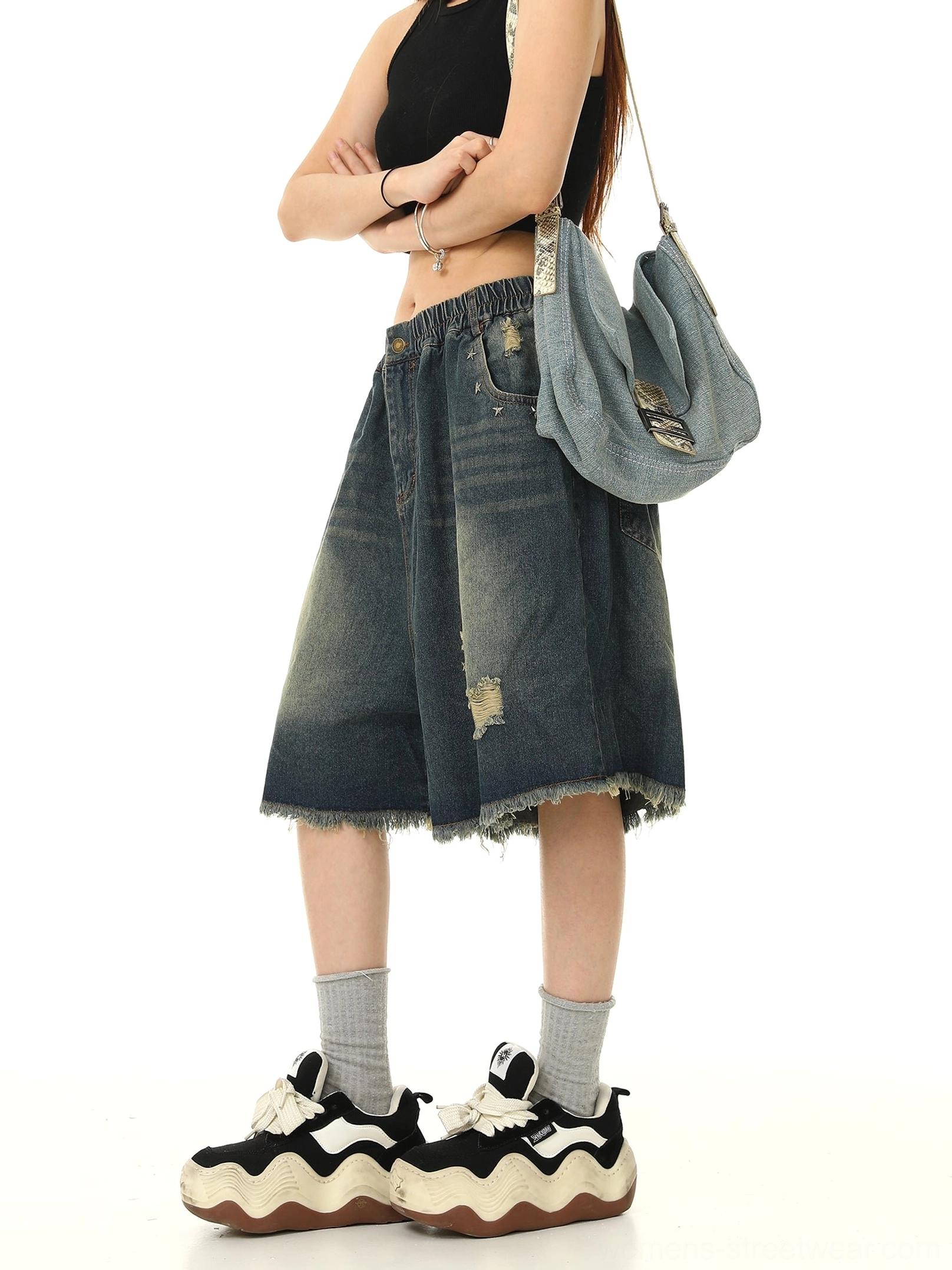 Right-side view of relaxed wide-leg distressed denim Bermuda shorts with side pockets, faded blue wash, and raw frayed hems