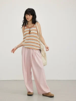 Blush pink relaxed wide-leg streetwear pants styled with a striped tank top in a minimalist studio outfit