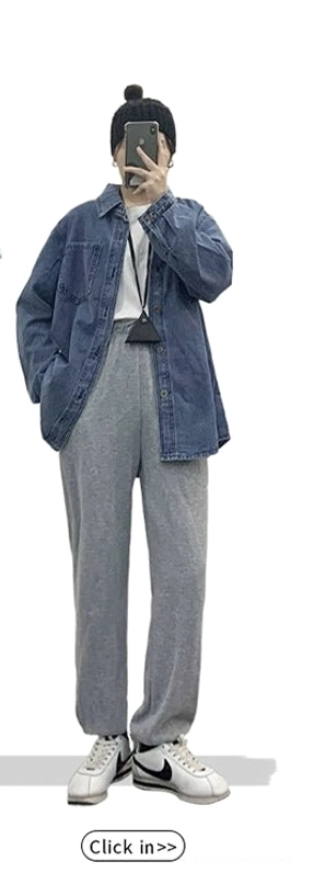 Relaxed women's blue denim shirt jacket styled with grey sweatpants, white sneakers, and a beanie for casual streetwear