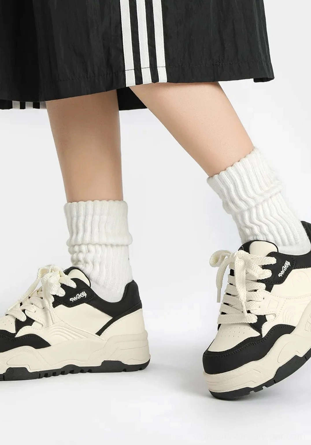 Retro black and white platform sneakers shown from the side with thick white socks, black toe caps, heel overlays, and textured outsole
