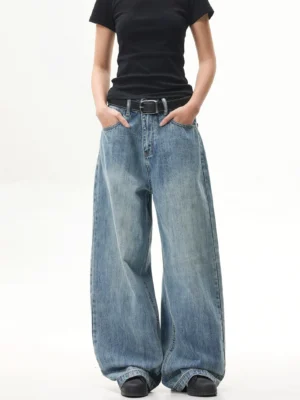 Three-quarter view of retro faded blue baggy jeans showing the oversized wide-leg fit, waistband, zip fly, and front pockets