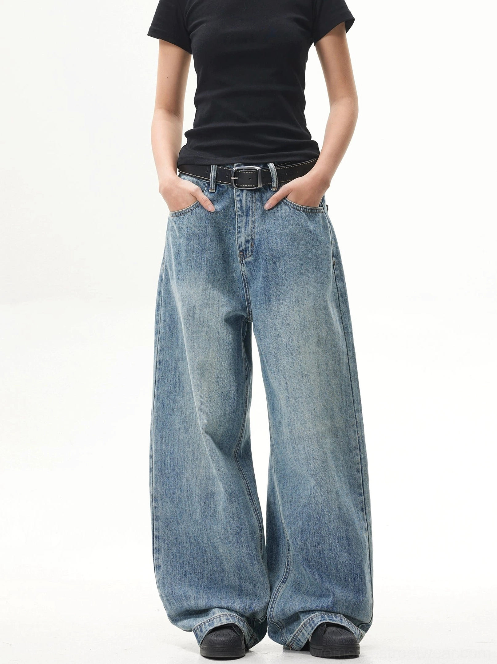 Three-quarter view of retro faded blue baggy jeans showing the oversized wide-leg fit, waistband, zip fly, and front pockets