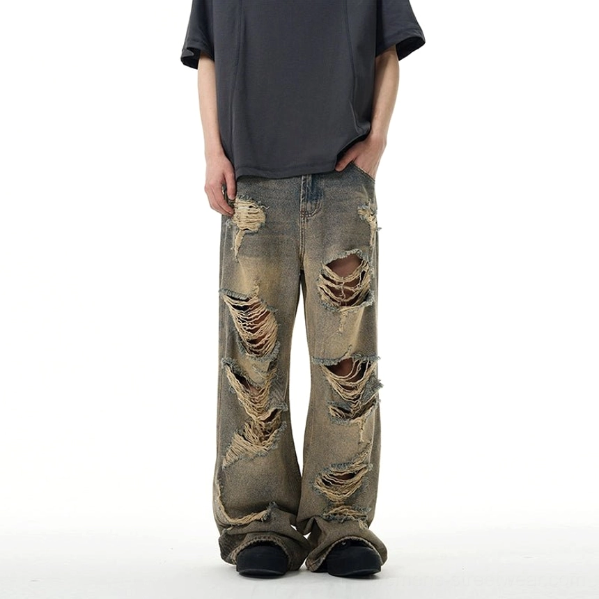 Front three-quarter view of retro blue distressed wide-leg ripped jeans with multiple front leg holes and relaxed fit