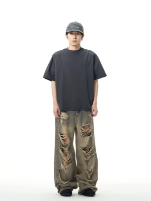 Full front view of oversized retro blue wide-leg ripped jeans on a model wearing a baseball cap and dark casual t-shirt