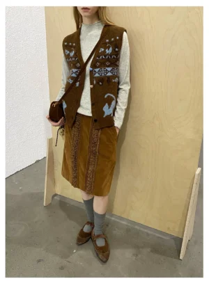 Side view of a retro brown corduroy midi skirt with lace trim styled in layered vintage streetwear against a wooden studio background