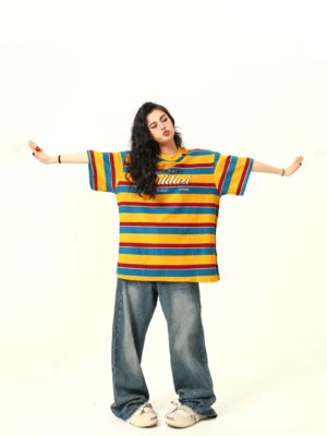Back view of an oversized retro striped streetwear tee showing the relaxed dropped-shoulder fit with wide-leg denim