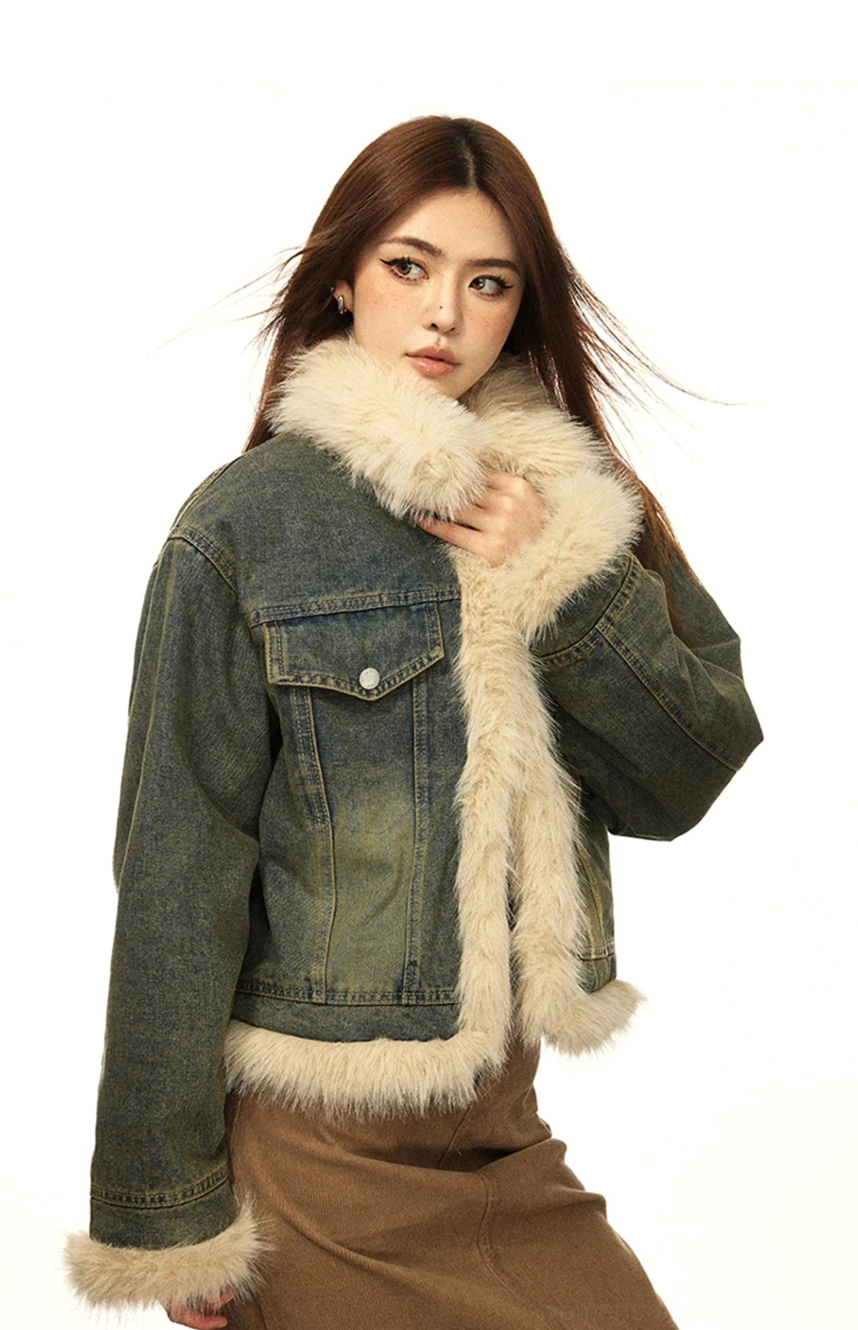 Woman touching the faux fur collar of a vintage retro denim jacket styled with a brown midi skirt and winter streetwear boots
