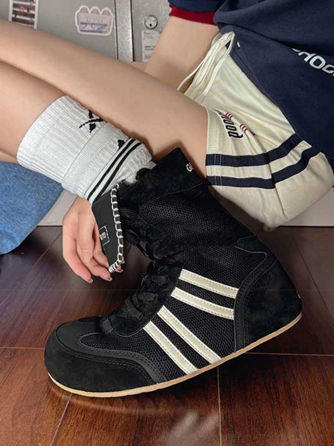 Black retro high-top boxing trainer boot with white contrast side stripes, mesh upper, and fold-over tongue worn indoors