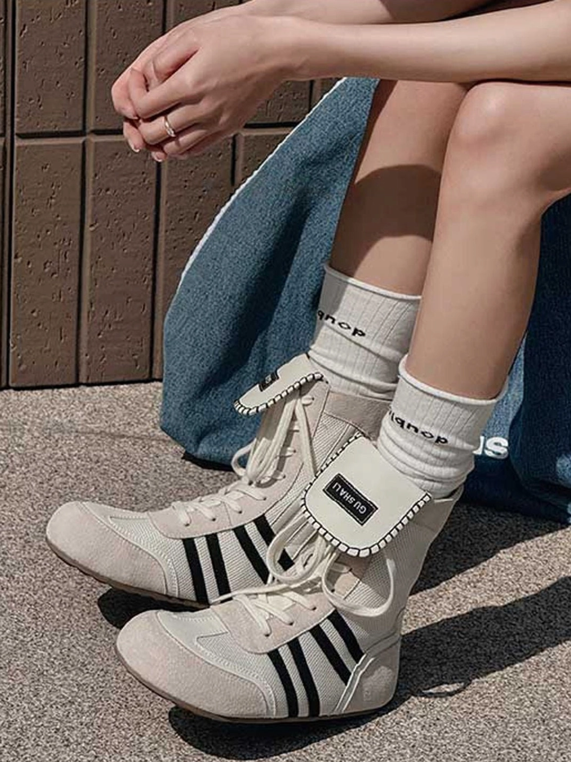 Light beige retro high-top boxing trainer boots with black stripes styled with denim on an indoor concrete floor