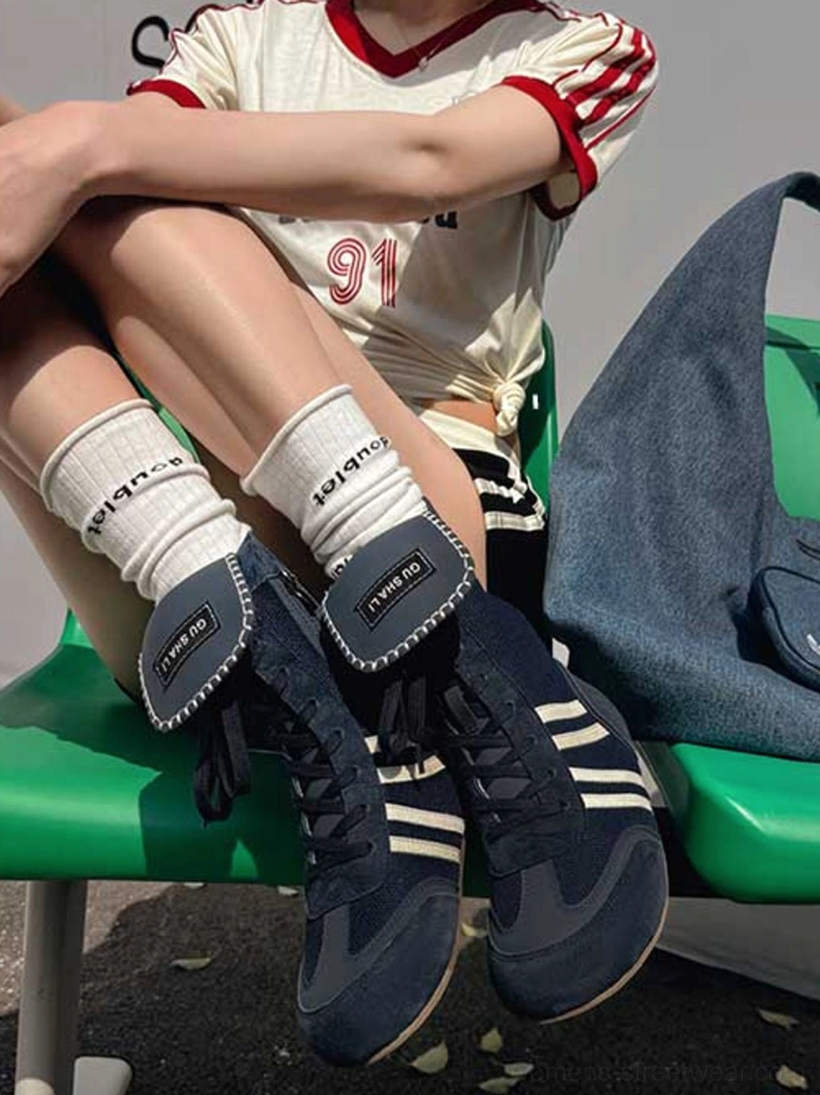 Navy blue high-top boxing trainer boots with white side stripes styled with a retro sports jersey and crew socks