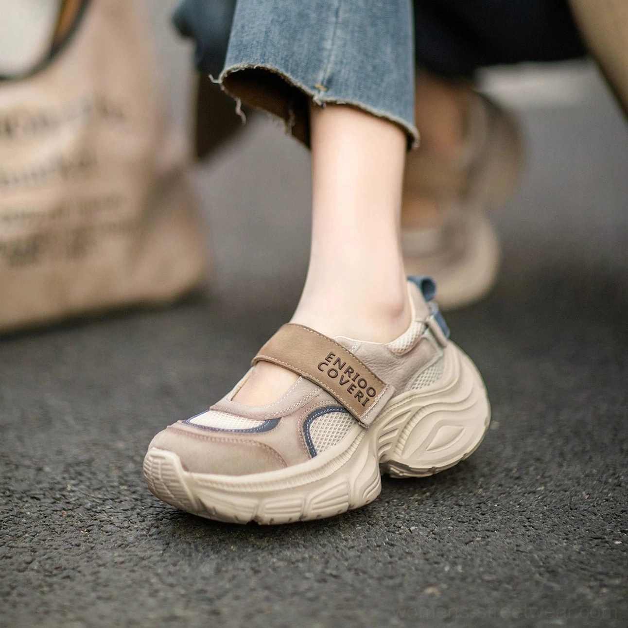 Close-up of retro Mary Jane platform sneaker with tan printed strap, blue accent panel, breathable mesh upper, and thick sculpted rubber platform sole