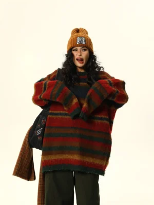 Front view of red multicolor striped fuzzy oversized crew neck sweater styled with dark green wide-leg pants and a plaid scarf