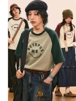 Color-block raglan graphic tee shown in a three-quarter front group studio view with relaxed Korean streetwear styling