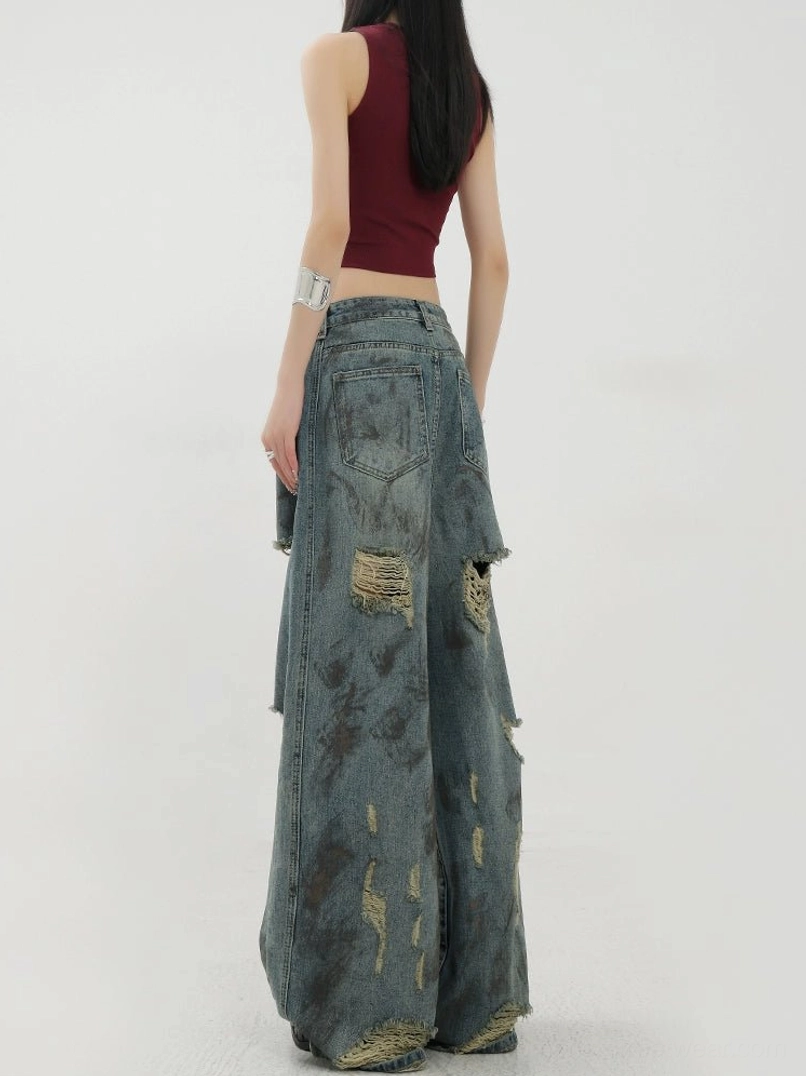 Front three-quarter view of retro tie-dye washed blue jeans with frayed distressed patterns across the wide legs