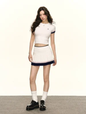 Retro varsity cropped knit tee and high-waisted pleated mini skirt outfit in ivory with navy and red striped trim front full body view