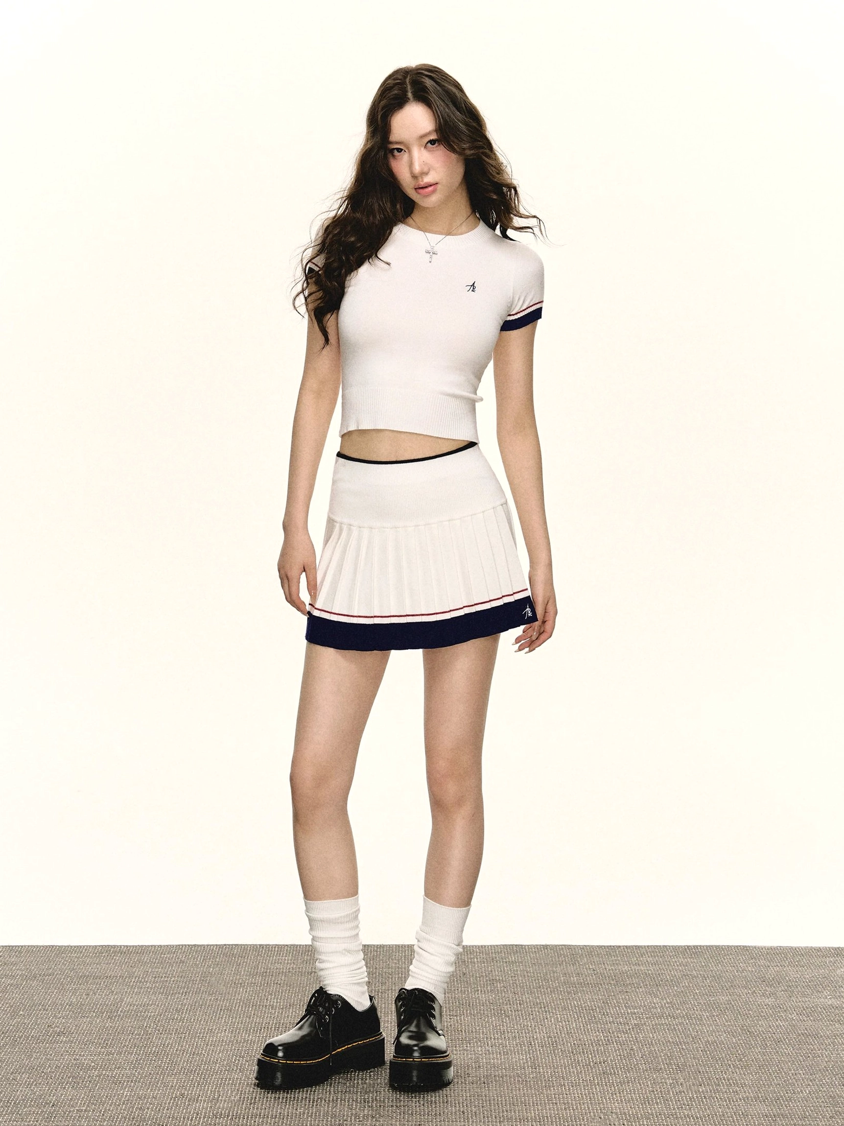 Retro varsity cropped knit tee and high-waisted pleated mini skirt outfit in ivory with navy and red striped trim front full body view